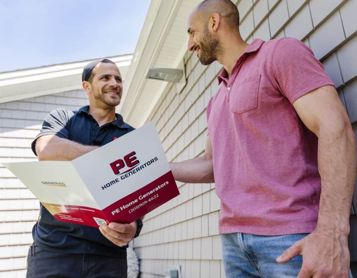 Two men shaking hands, one holding a PE Home Generators brochure.